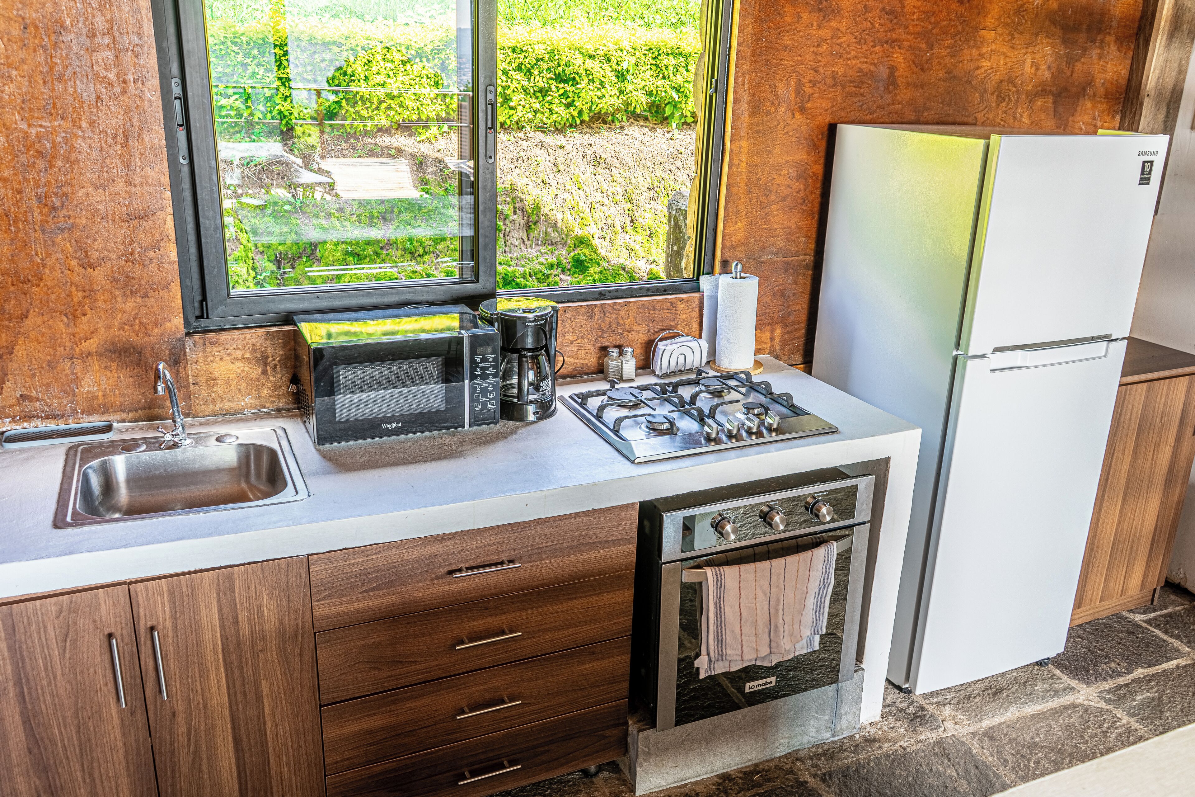 Une cuisine compacte équipée d’un évier, d’une cuisinière, d’un four à micro-ondes et d’un réfrigérateur.