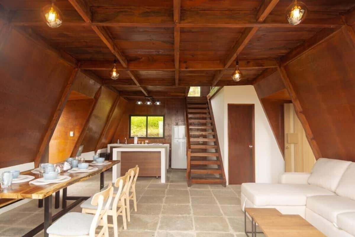 An attic-style room with a dining area, kitchen, and a staircase leading to an upper level.