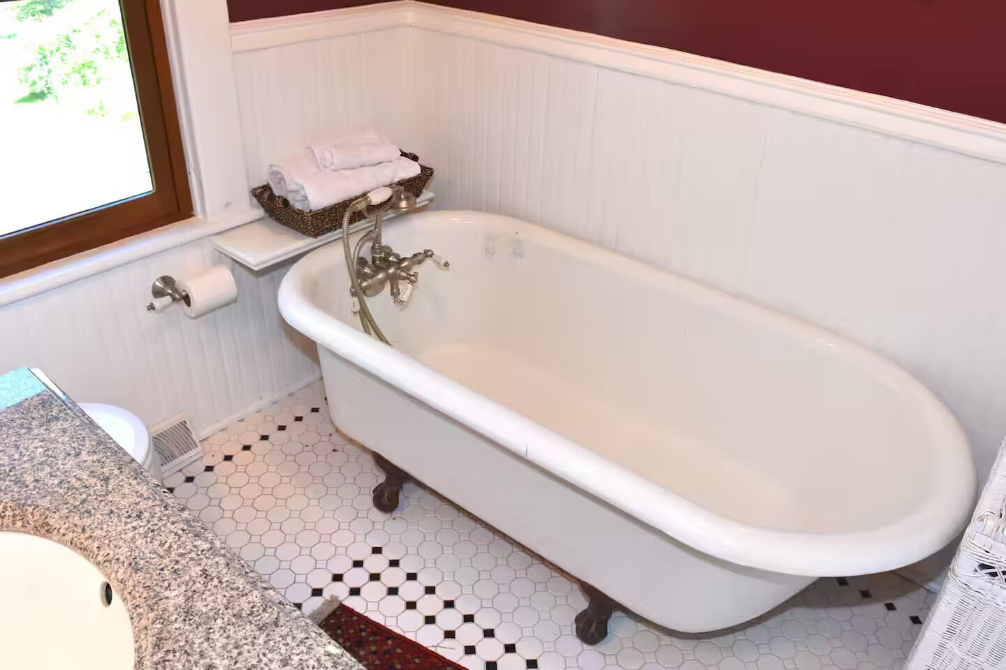 A bathroom with a white bathtub, a toilet, and a window.