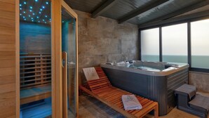 A spa room with a hot tub, wooden benches, and a view of the ocean. - Villa Bavigo in Marcana (Marcana)