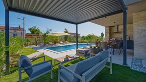 A covered outdoor area with a pool, seating, and a kitchen area. - Villa Bavigo in Marcana (Marcana)