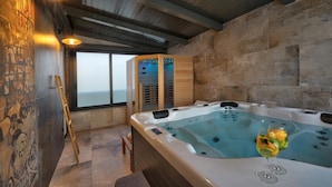 A spa room with a hot tub, wooden beams, stone walls, and a view through a large window. - Villa Bavigo in Marcana (Marcana)