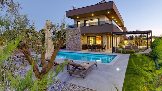 A modern house with a swimming pool, outdoor seating, and a stone wall. - Villa Bavigo in Marcana (Marcana)