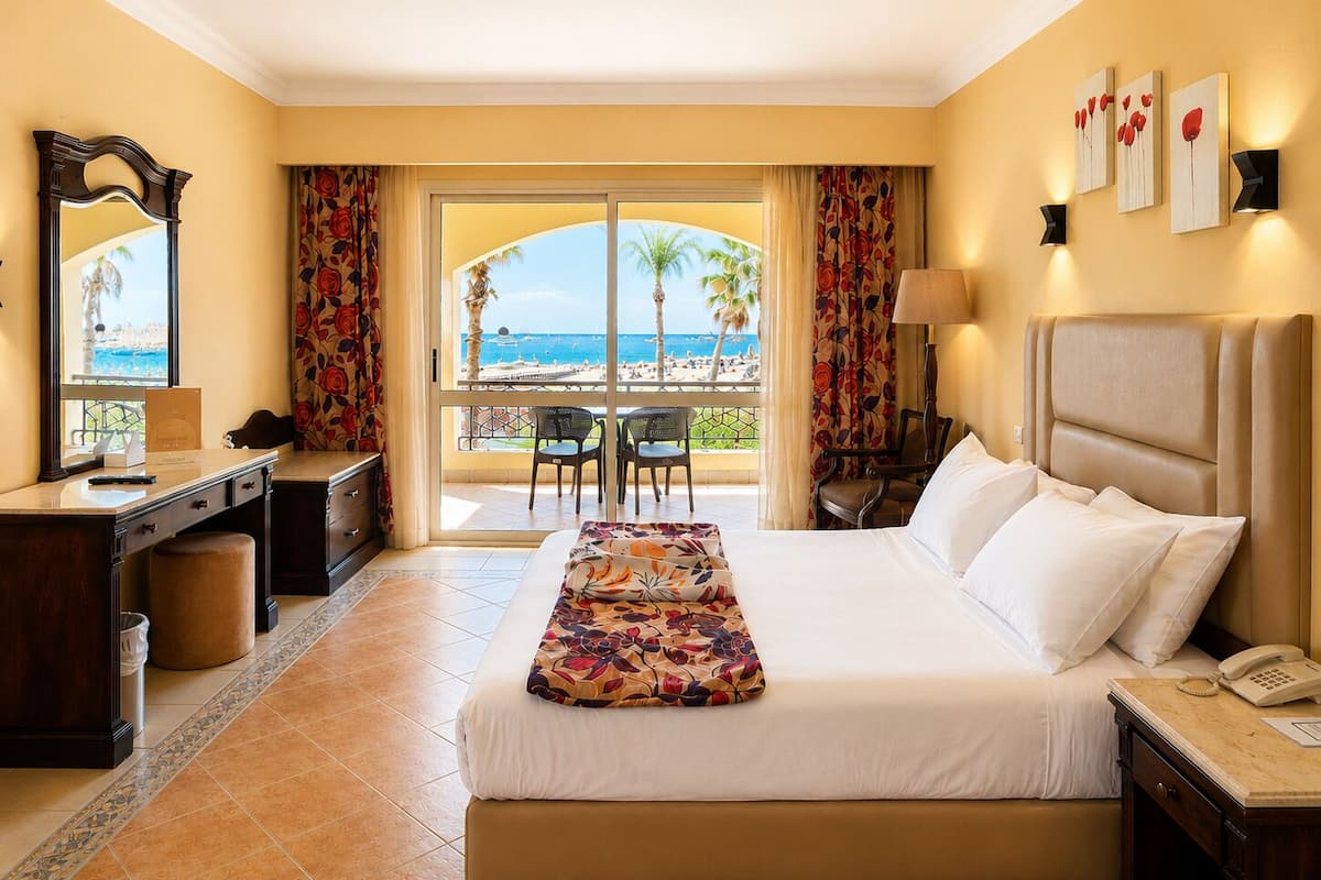 Habitación de hotel con cama, escritorio, silla y vista al mar.
