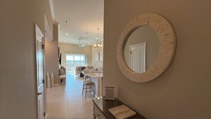 Un vaste espace de vie agrémenté d’un grand miroir, d’une table à manger et offrant une vue sur un balcon, accessible par une porte-fenêtre coulissante.