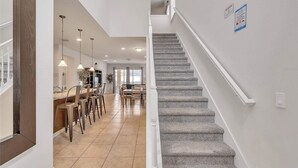 A spacious kitchen with a dining area, a staircase, and a view of the outdoors. - Family-Friendly Villa w Pool, Hot Tub & Game Room (Kissimmee)