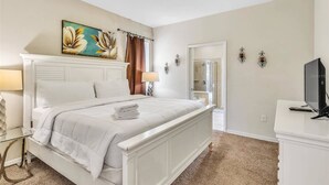 A bedroom with a bed, a painting, a shower, and a TV. - Family-Friendly Villa w Pool, Hot Tub & Game Room (Kissimmee)