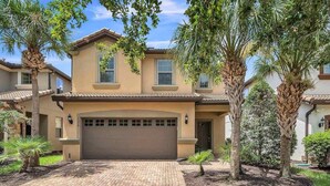 A two-story house with a brown garage door, surrounded by palm trees and a brick driveway. - Family-Friendly Villa w Pool, Hot Tub & Game Room (Kissimmee)