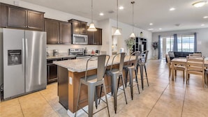 A modern kitchen with a central island, stainless steel appliances, and pendant lighting. - Family-Friendly Villa w Pool, Hot Tub & Game Room (Kissimmee)