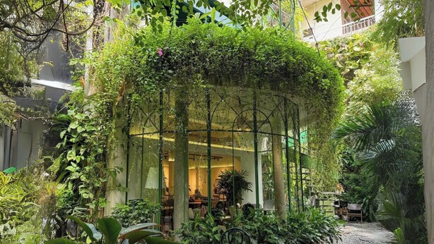 Um jardim interno com área de estar, plantas em vasos e um caminho de cascalho.