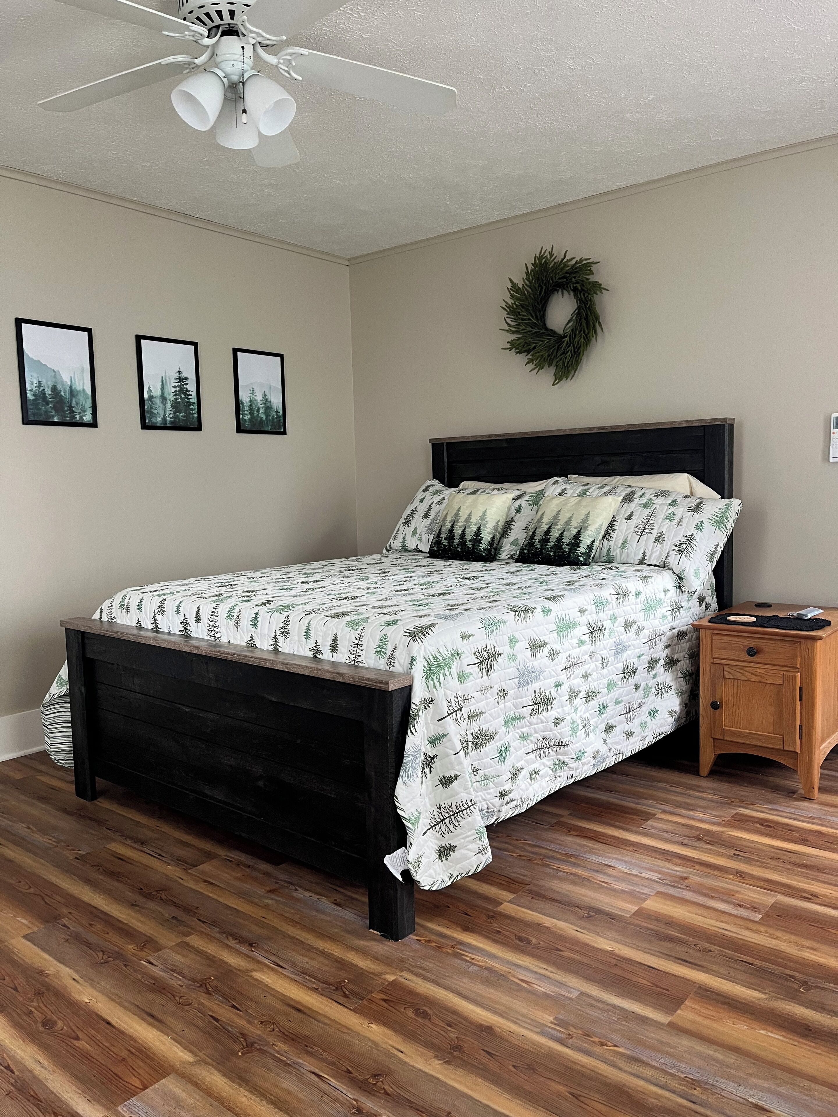 A bedroom with a bed, wooden nightstand, and a ceiling fan.