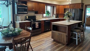 Una cocina moderna con armarios de madera, electrodomésticos de acero inoxidable y una isla central.
