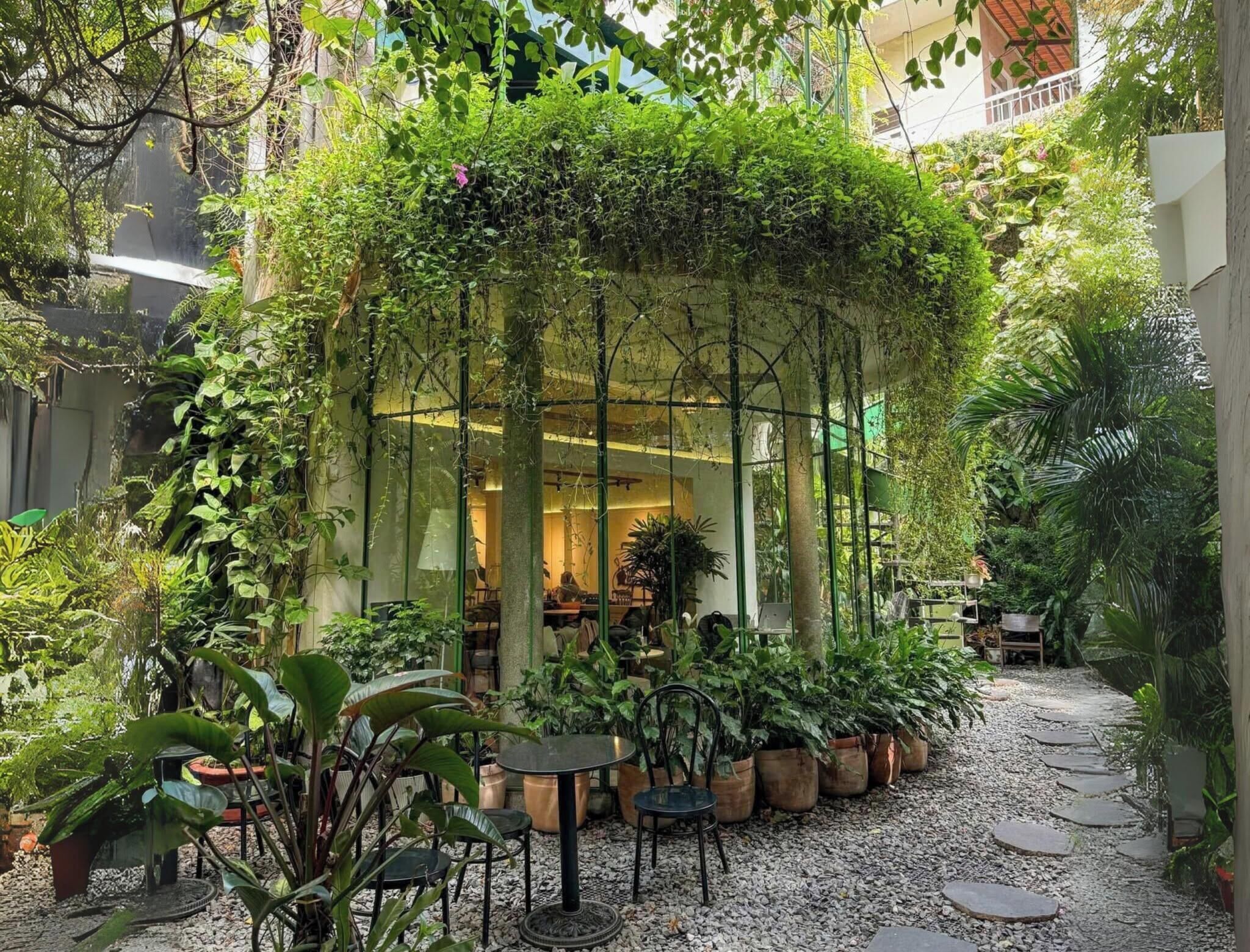 An indoor garden with a seating area, potted plants, and a gravel path.
