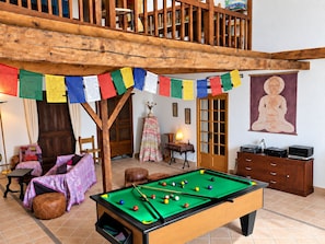 Ein Zimmer mit Pooltisch, Holzbalkendecke und bunten Gebetsfahnen.