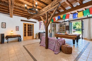 A spacious room with a wooden ceiling, a billiards table, and colorful flags. - Soleil de Cocagne – Old Stone & Charm near the Canal du Midi (Lagarde)