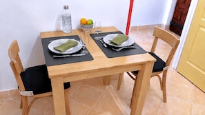 Ein Esstisch für zwei Personen, gedeckt mit schwarzen Platzsets, Tellern und Besteck.