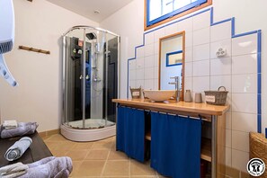 A bathroom with a glass shower enclosure, a sink with a marble basin, and a mirror above the sink.