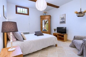 Ein Schlafzimmer mit einem Bett, einem Fernseher, einer Lampe und einem Fenster.