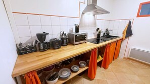Eine Küche mit Holztischplatte, einem Toaster, einer Kaffeemaschine, einem Wasserkocher, einem Herd und einem Spülbecken.