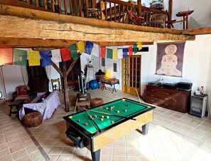 A room with a pool table, a meditation statue, and a wooden ceiling.