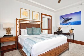Ein Hotelzimmer mit einem hölzernen Bett, einem Schreibtisch, einem Stuhl, einem großen Fenster und Kunstwerken an den Wänden.