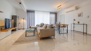Ein modernes Wohnzimmer mit Sofa, Couchtisch, Fernseher und Essbereich.