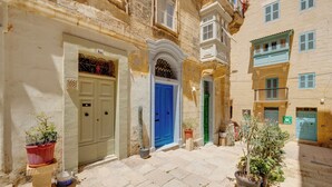 Una calle estrecha con edificios de arquitectura tradicional, incluyendo una puerta azul y una puerta verde.