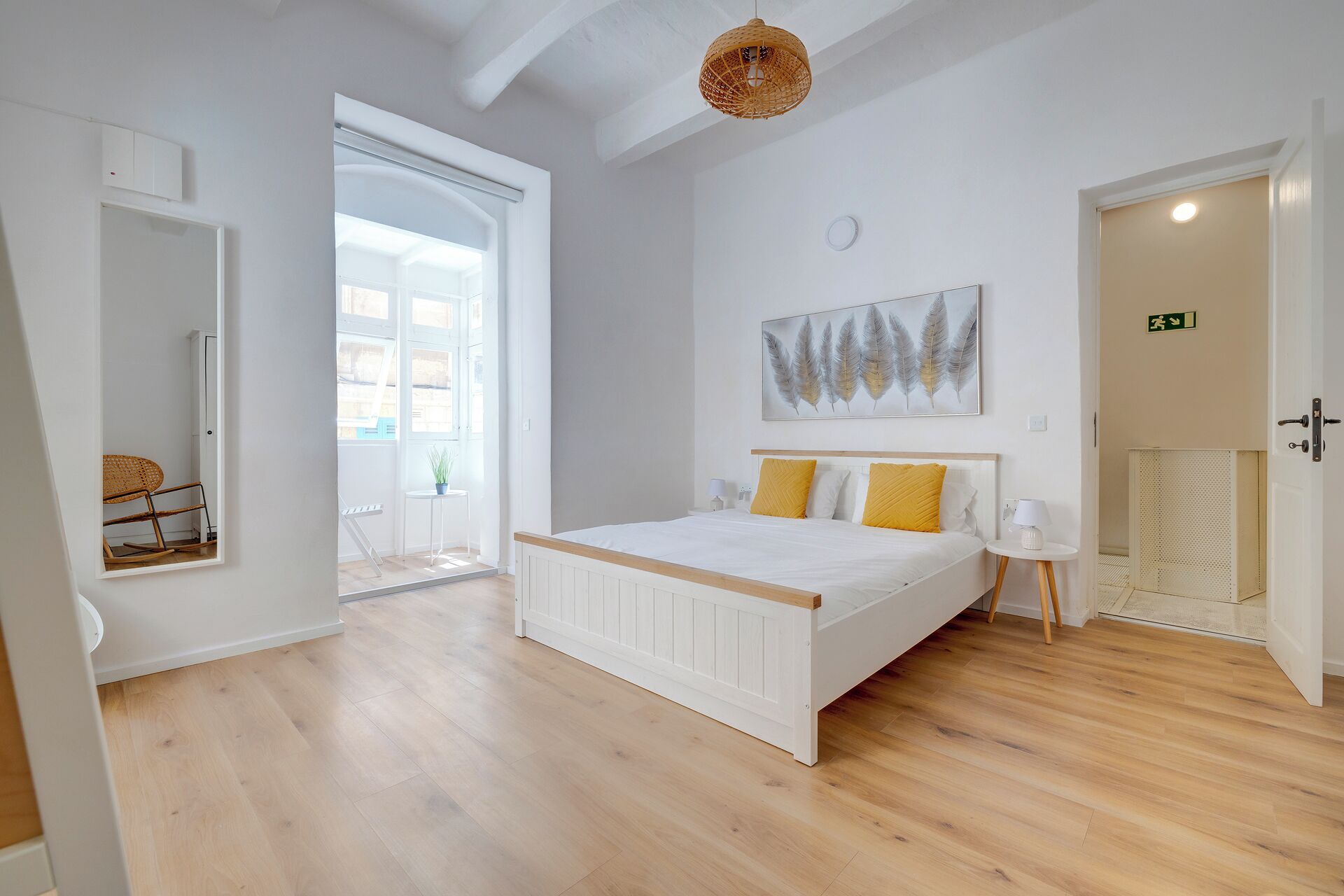 Ein Schlafzimmer mit einem großen Bett, einem Deckenventilator, einem Gemälde und Blick ins Freie.