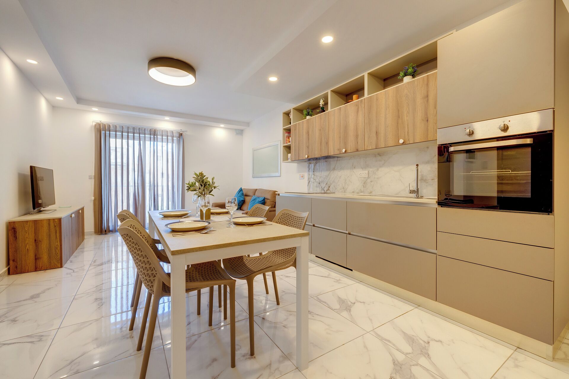 A modern kitchen with a built-in oven, wooden cabinets, and a dining area with a table set for four.