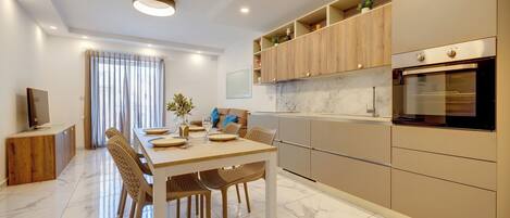 A modern kitchen with a built-in oven, wooden cabinets, and a dining area with a table set for four.