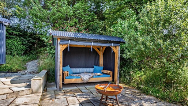 A wooden outdoor seating area with a swing, a fire pit, and a stone pathway. - 1 Bed in Withypool (oc-s29887) (Withypool)
