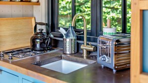 A kitchen with a gas stove, a kettle, a coffee maker, a toaster, and a window with a view of greenery. - 1 Bed in Withypool (oc-s29887) (Withypool)