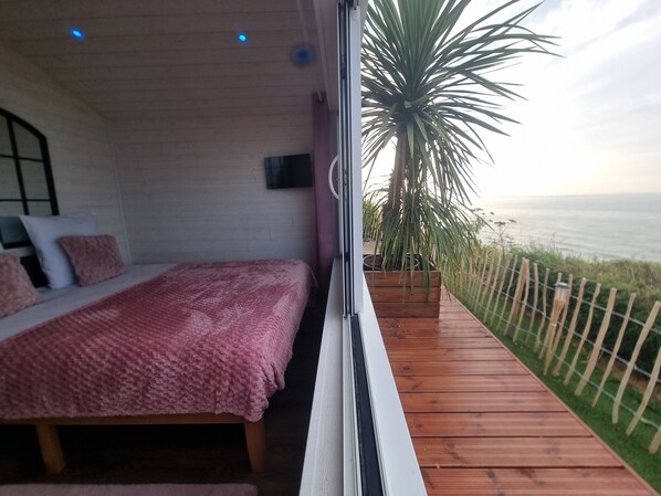 Une chambre avec un lit, une fenêtre et une vue sur l’océan.