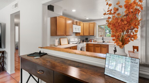 Una cocina moderna con armarios de madera, encimera blanca y un jarrón con flores naranjas.