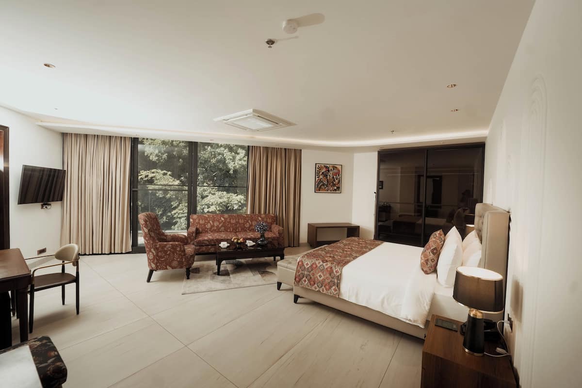 Quarto de hotel moderno com uma cama grande, um sofá, uma escrivaninha e uma televisão.