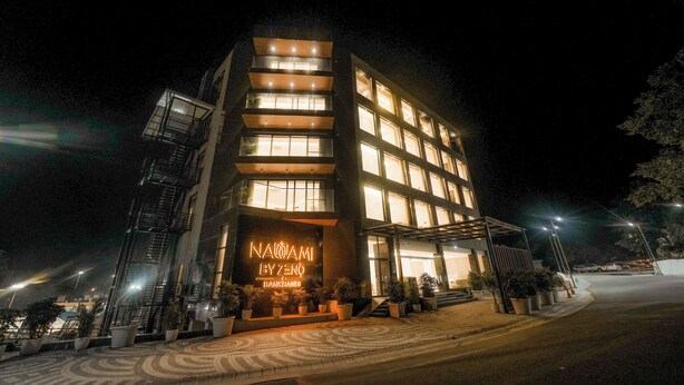 A modern hotel with a prominent entrance, multiple floors, and a well-lit facade. - NAMAMI BY ZENQ BANKHANDI (Dera Gopipur)