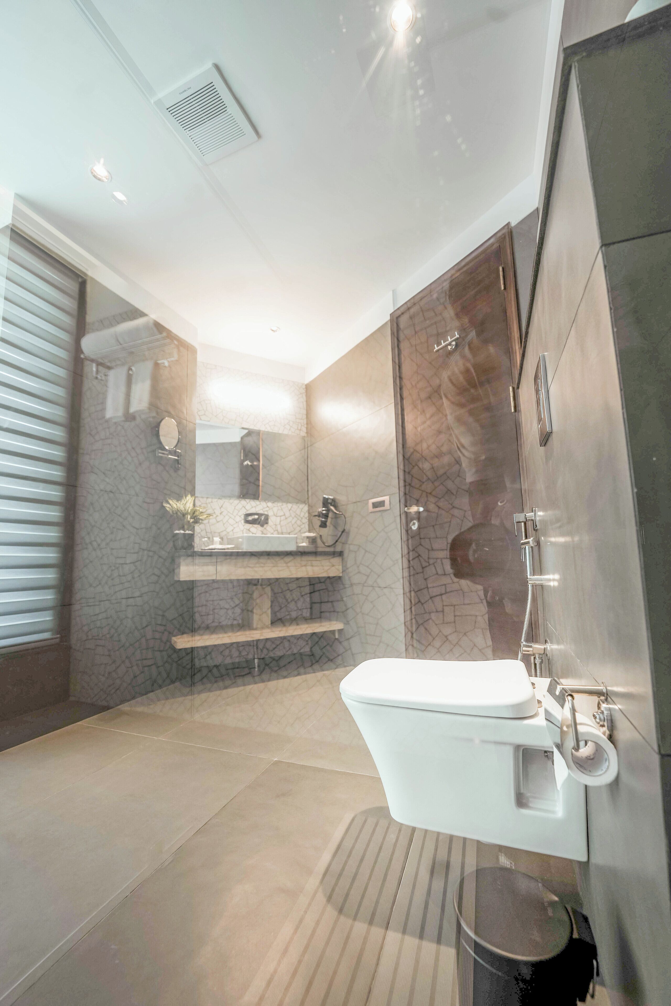 A modern bathroom with a glass-enclosed shower, a white sink, and a marble-tiled floor.