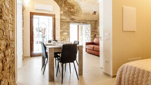 Un comedor con pared de piedra, una mesa con sillas y vistas a la calle.