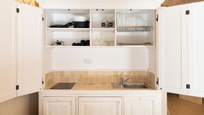 Una cocina compacta con armarios blancos, un lavamanos empotrado y un salpicadero azulejado.