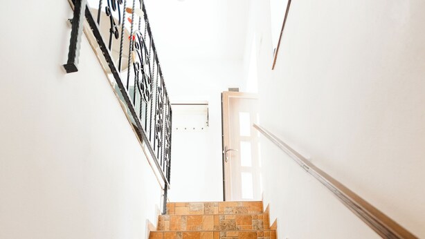 Una escalera con baldosas marrones que lleva a una puerta al final.