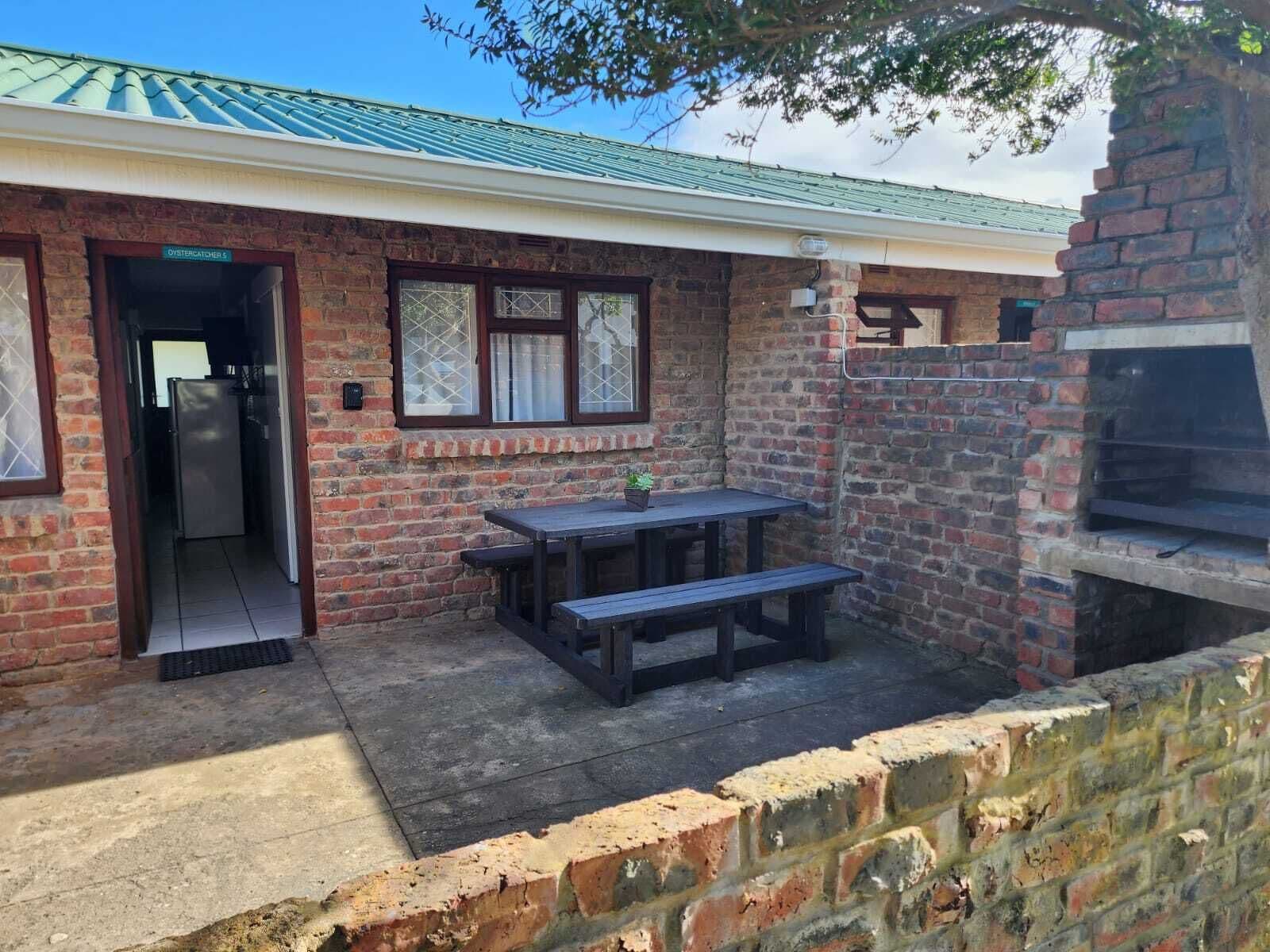 Un bâtiment en briques doté d’un patio couvert, d’une table et de bancs, ainsi que d’un four en briques.