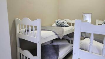 A room with three bunk beds, a bedside table, and a mirror.