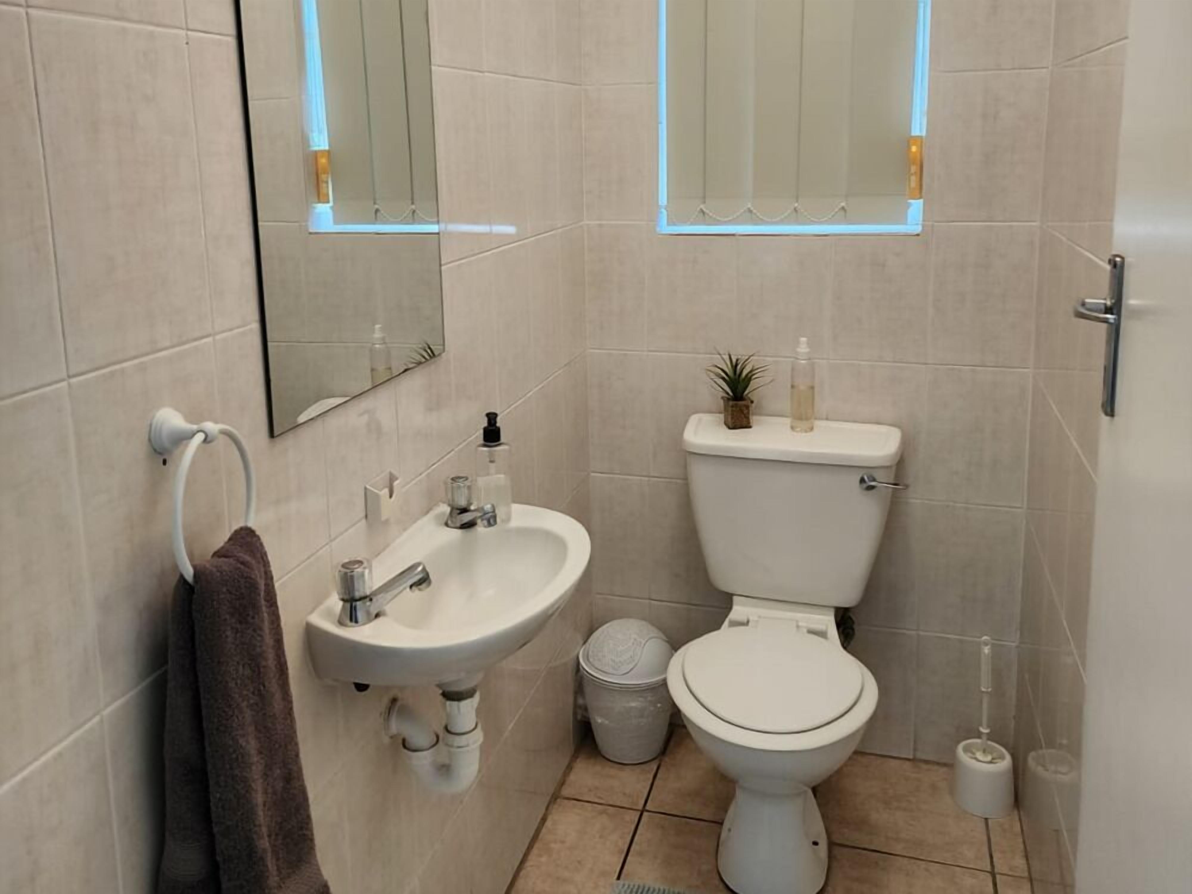 A bathroom with a sink, toilet, and mirror.