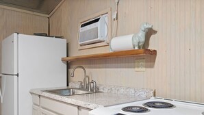 Eine Küche mit einem weißen Kühlschrank, einer Granitarbeitsplatte, einer Edelstahlspüle und einem weißen Herd.