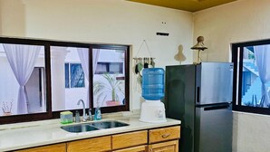 A compact kitchen with wooden cabinets, a sink, a water dispenser, and a refrigerator. - Hidden Gem: Bright and spacious apartment, just steps from Oaxaca’s best spots!  (Oaxaca de Juárez)