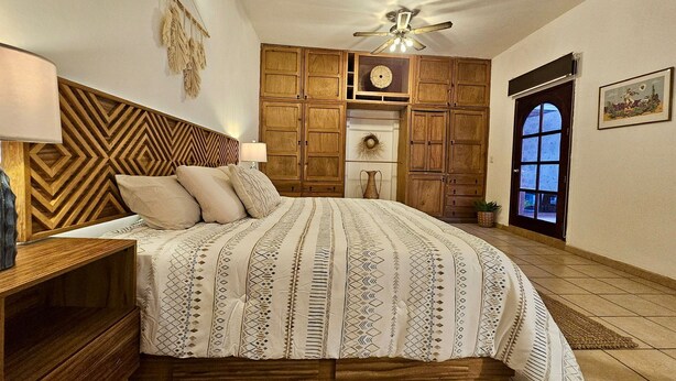 A bedroom with a large bed, wooden headboard, a ceiling fan, and a door with a view. - Hidden Gem: Bright and spacious apartment, just steps from Oaxaca’s best spots!  (Oaxaca de Juárez)