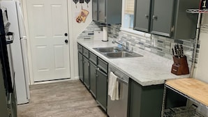 A kitchen with dark cabinets, a marble countertop, a sink, and a ceiling fan. - AggieLand Vacation House!  Charming 3-BR 2-BA only 3 miles from Texas A&M Campus (Bryan)