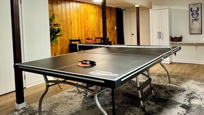 Un tavolo da ping pong in una stanza con parete in legno, una porta e un armadio.