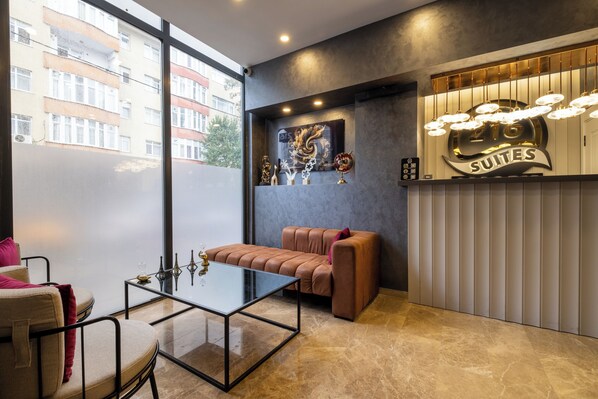 A modern hotel lobby with a glass coffee table, leather sofa, and a sign indicating 'Suites'. - 216 Star (Istanbul)