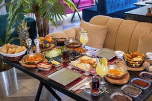 A buffet table with various dishes and drinks, surrounded by a sofa and a plant. - 216 Star (Istanbul)